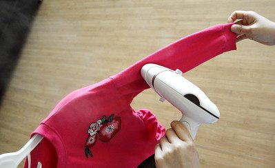 A woman's hand ironing a pink dress's sleeve