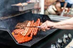 a-person-grilling-steaks-and-sausages