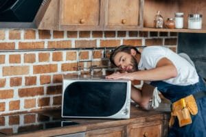 a repair man fixing a kitchen appliance