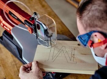 man cutting the letter M out of wood