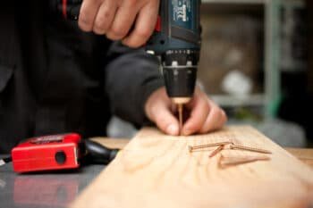 man driving screw into a wood plank