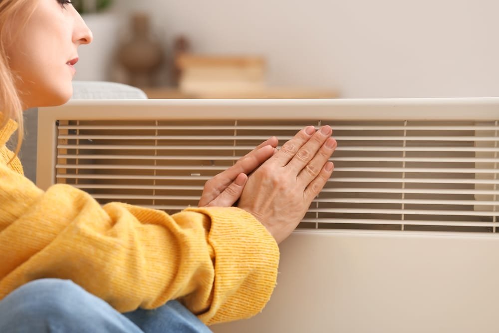 mature-woman-warming-hands-near-electric-heater-at-home-concept-of-heating-season