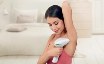 woman using handheld device on underarms