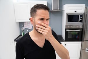 young man covers nose in smelly kitchen