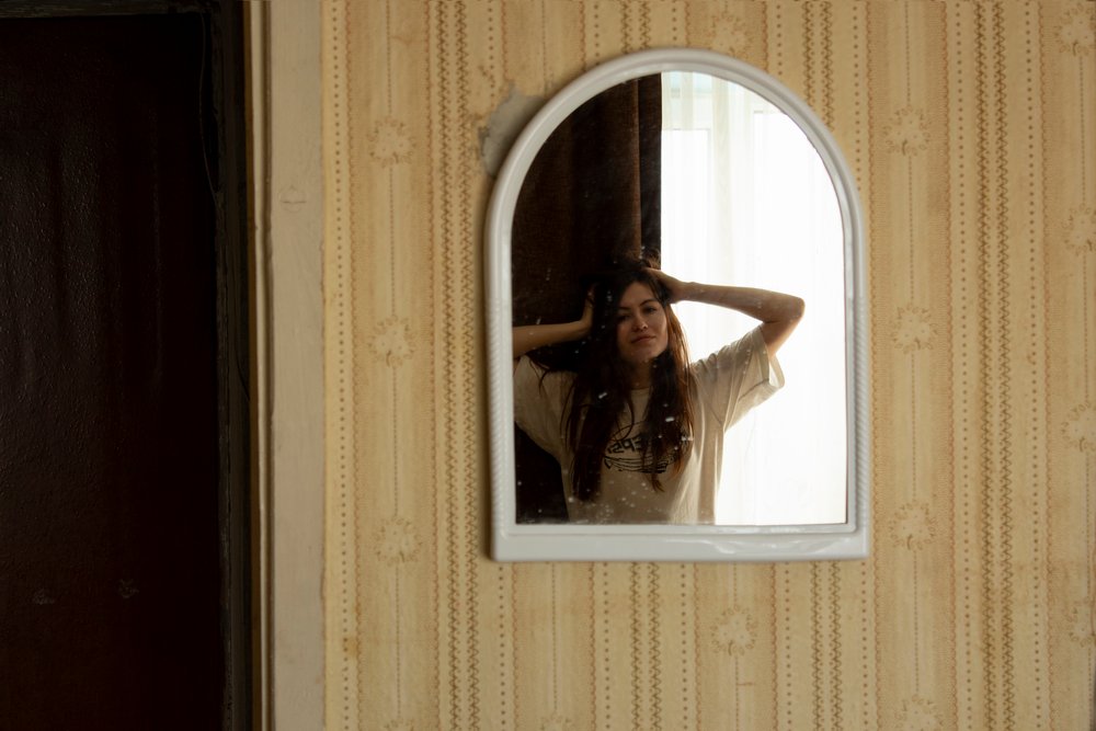 A woman is looking at her reflection