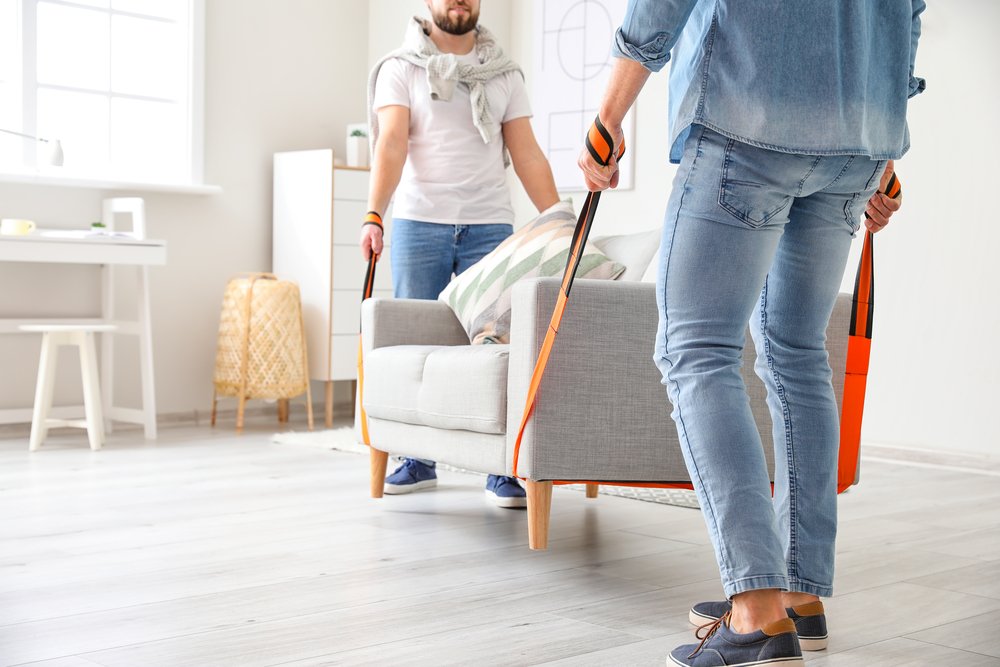 Men using cargo belt straps for carrying sofa