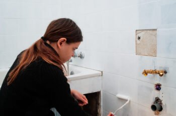 Young woman painting ceramic wall