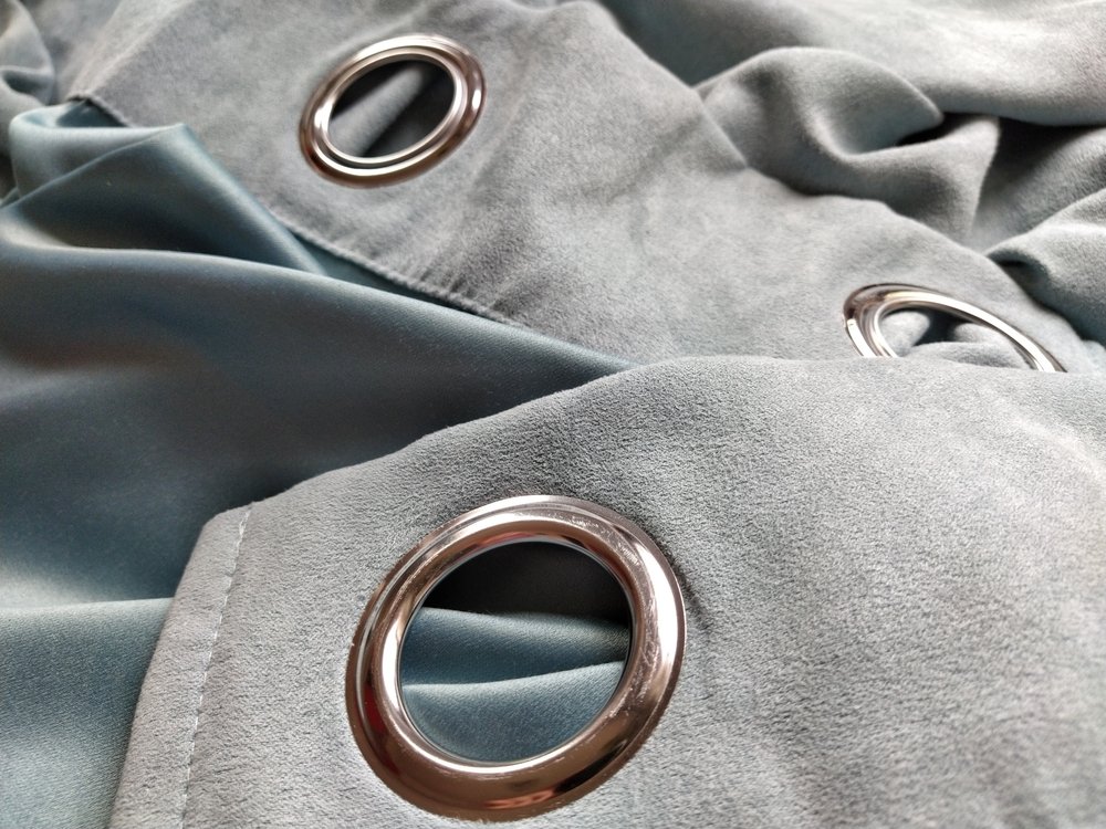 Two metal eyelets on gray-blue velvet curtains